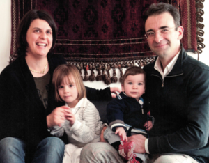 Vater und Mutter sitzen mit ihren beiden Kindern auf dem Schoß