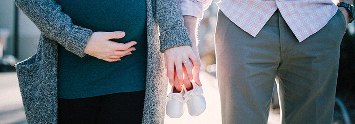 Schwangere Frau hält die Hand ihres Partners
