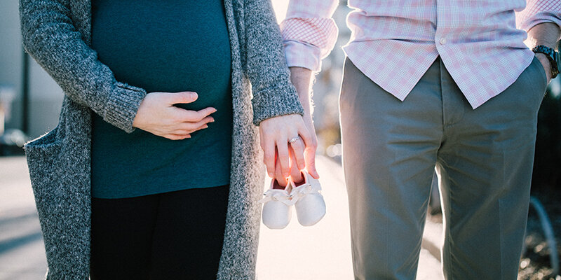 Schwangere Frau hält die Hand ihres Partners