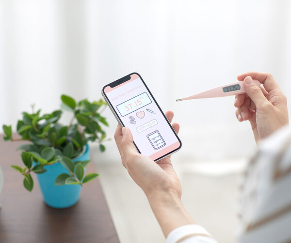 Eine junge Frau gibt ihre gemessene Basaltemperatur in eine App ein