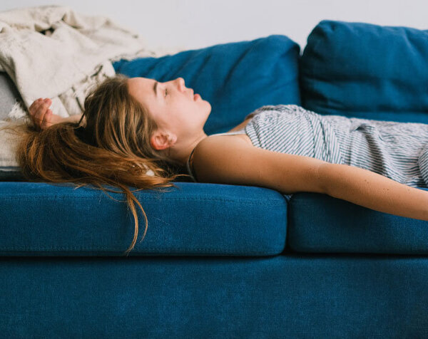Eine junge Frau liegt müde auf der Couch 