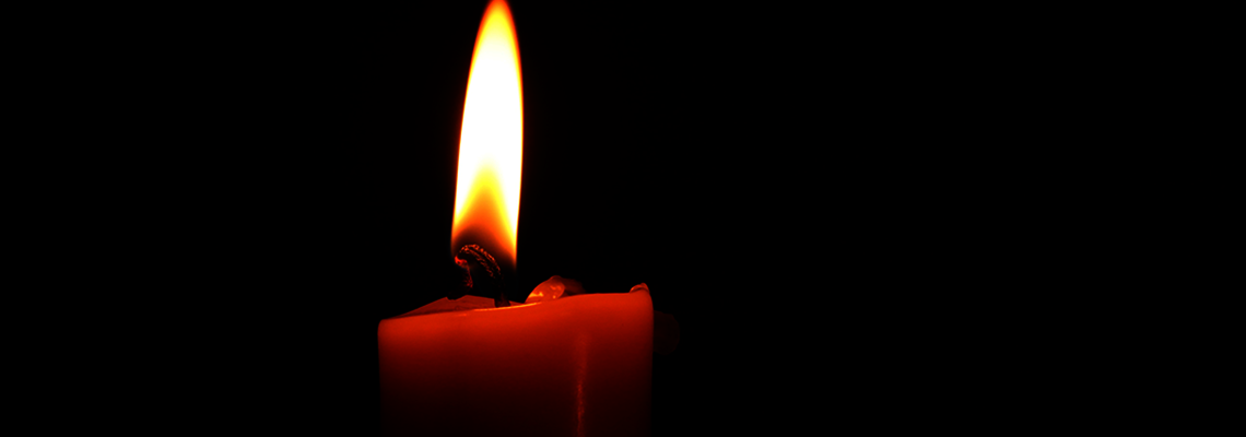 Eine rote brennende Kerze vor schwarzem Hintergrund